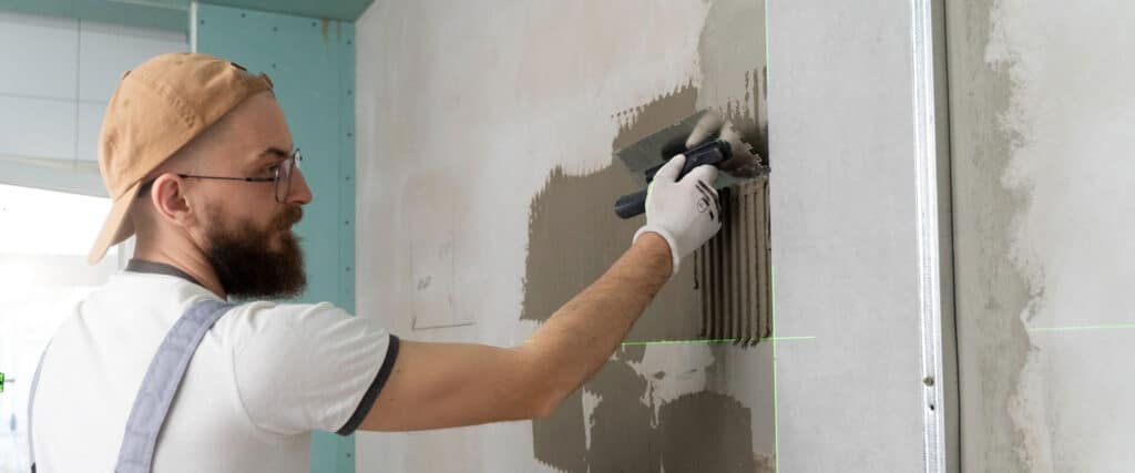 Homem aplicando argamassa na parede.