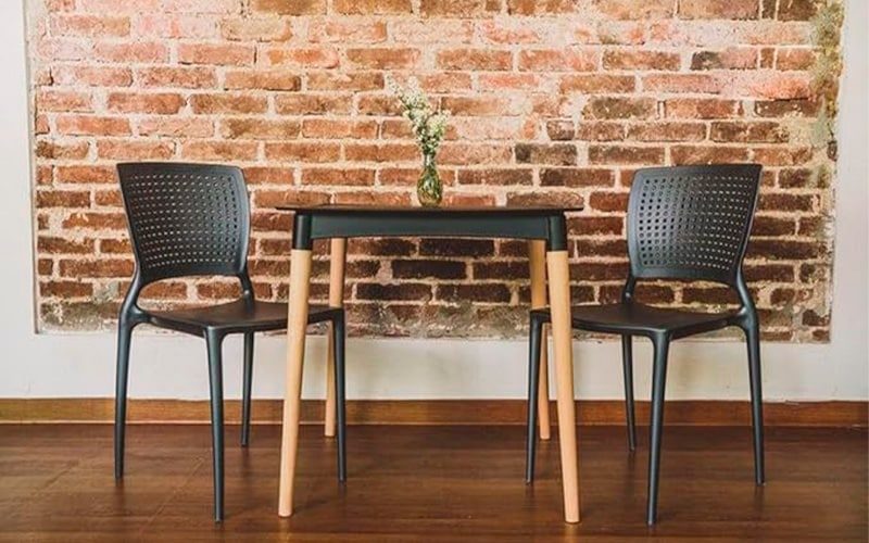 Imagem de conjunto de mesa e cadeiras pretas e parede de tijolos de fundo